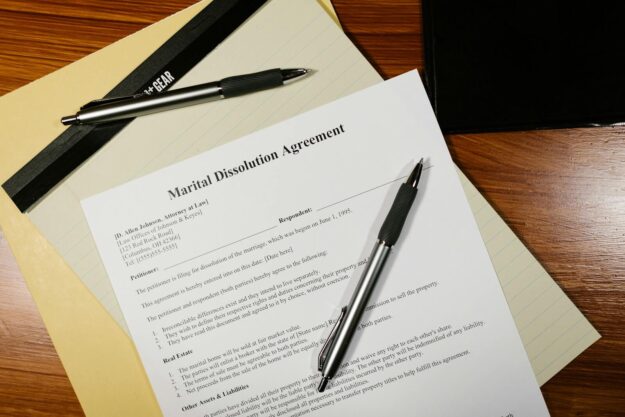 Photo by RDNE Stock project Flat lay of a marital dissolution agreement form with pens and files on a desk.