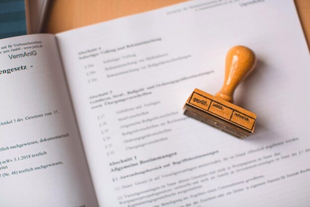 Photo by Markus Spiske Close-up of a legal document with a wooden stamp placed on top, highlighting verification.